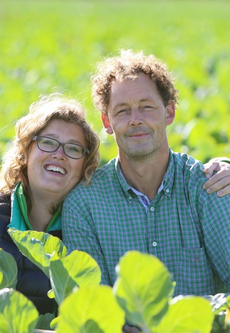 Die Gründer Jan und Linda stehen mitten im blühenden Feld und schauen in die Kamera.