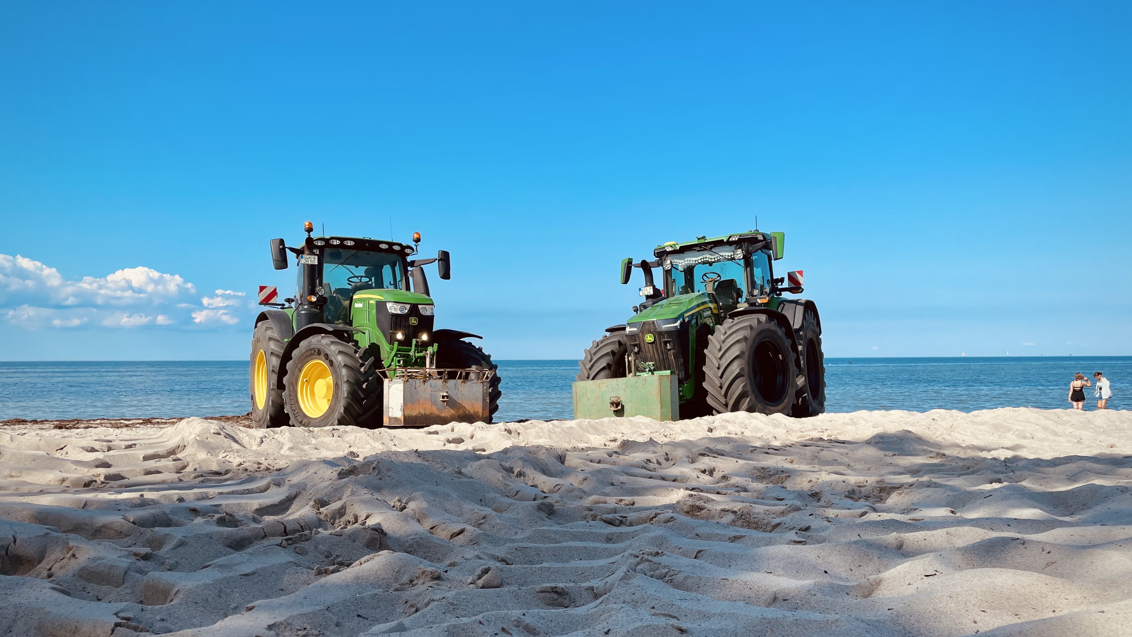 Zwei Traktoren stehen am Strand